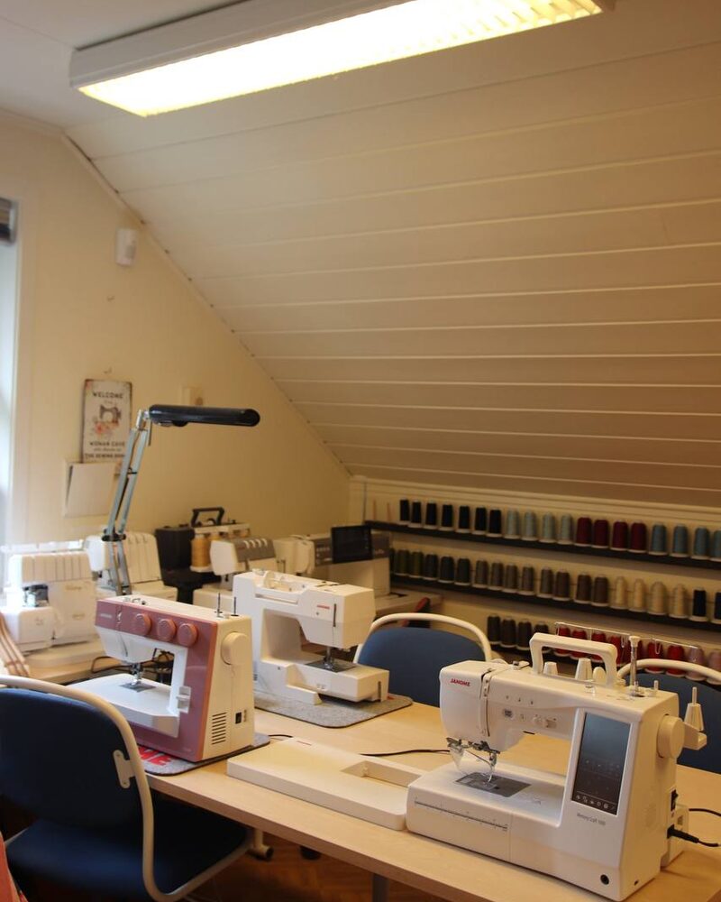 Flere symaskiner på et arbeidsbord i et syrom